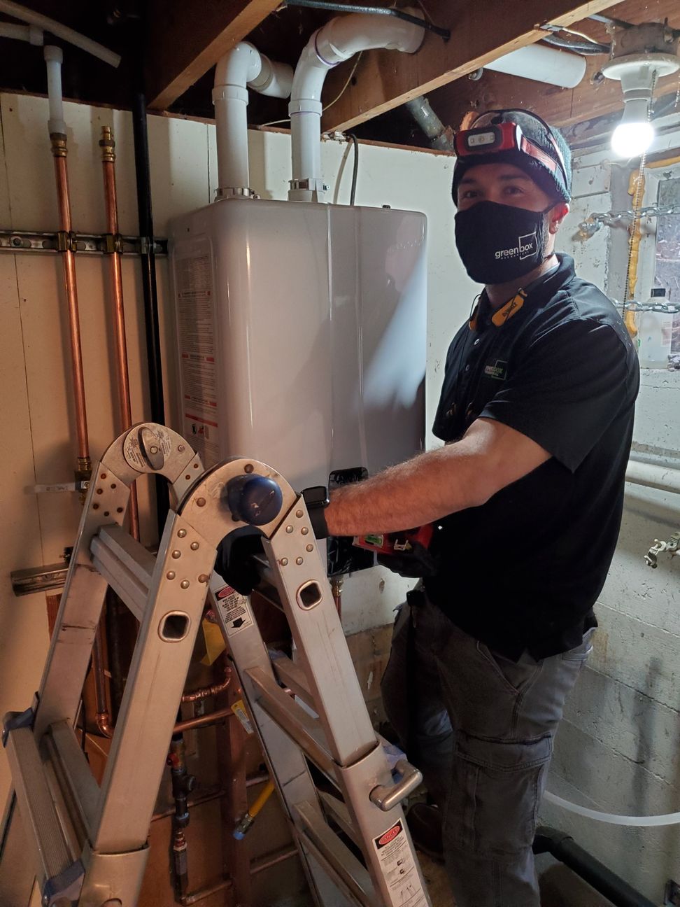Plumber installing a tankless water heater - Green Box Mechanical